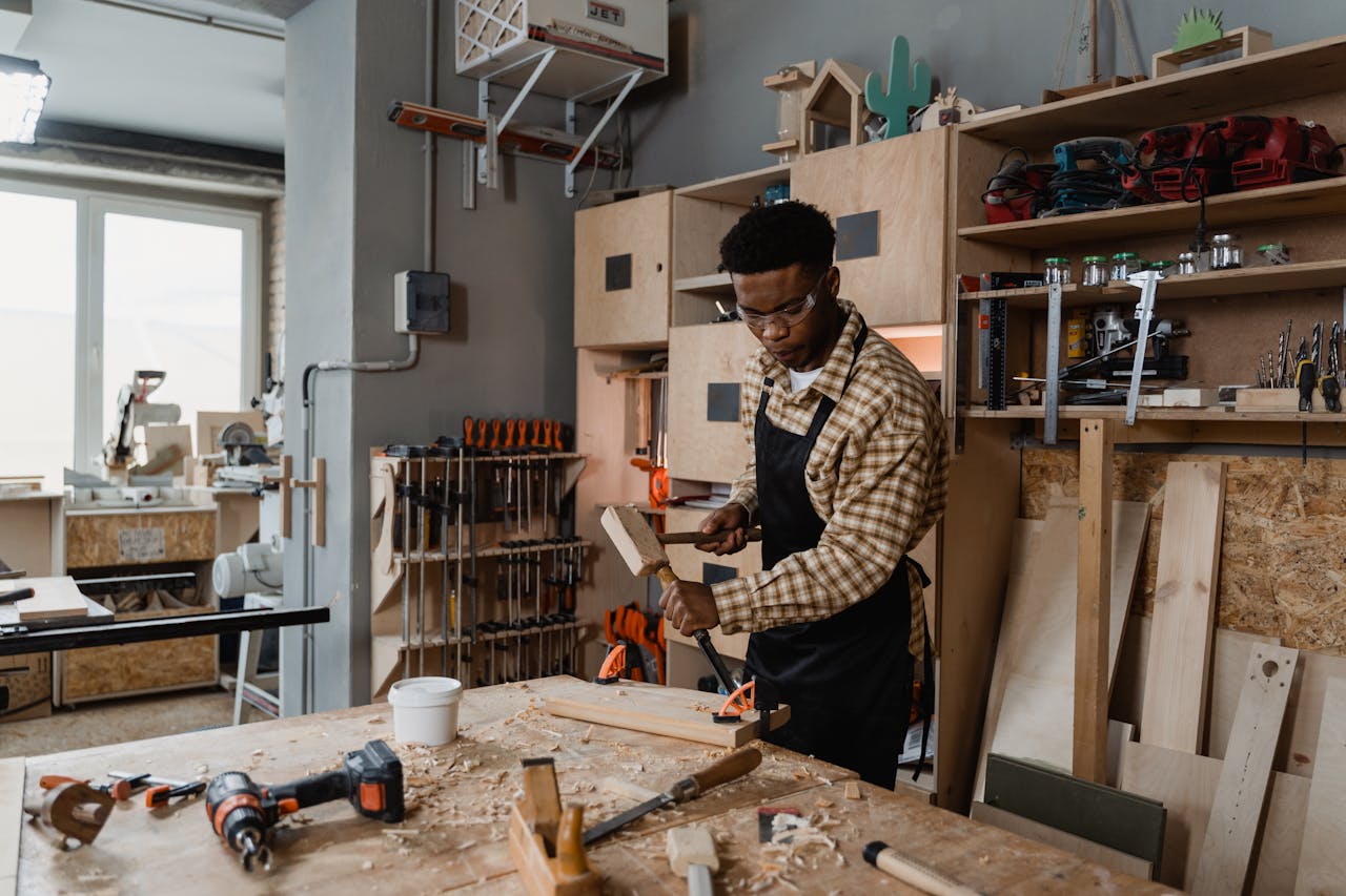 A professional woodworker carving timber in a well-equipped workshop, showcasing craftsmanship.